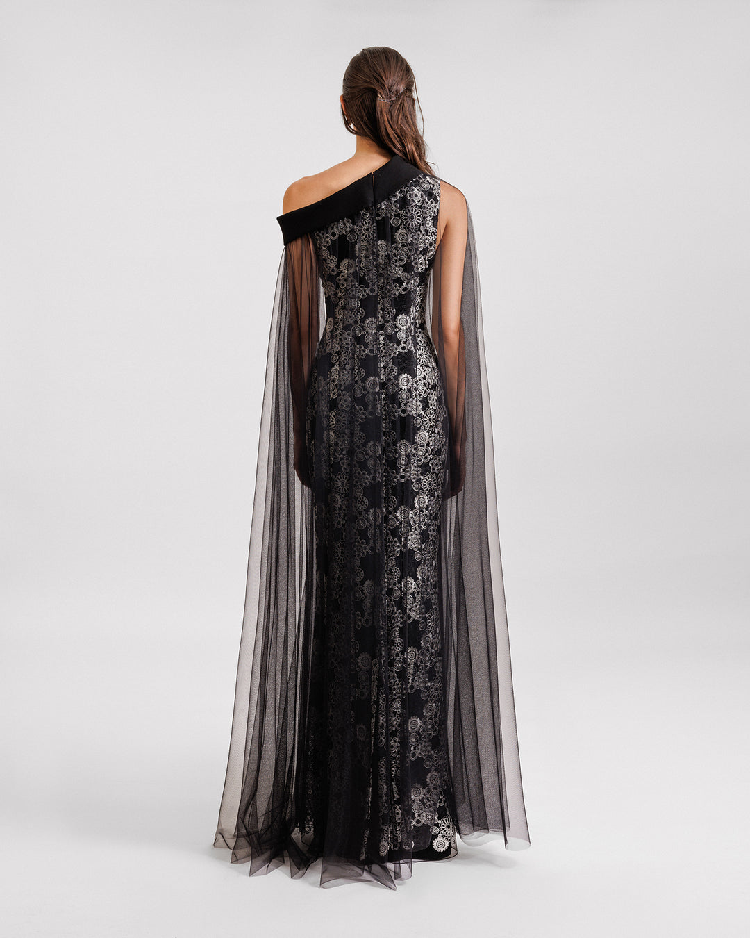 The back of an embroidered asymmetrical neckline black evening dress with a tulle overlay.