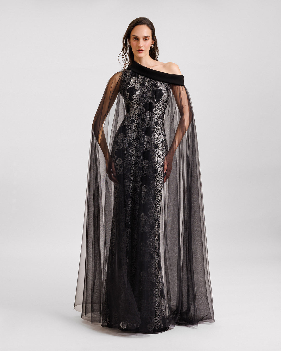 An embroidered asymmetrical neckline black evening dress with a tulle overlay.