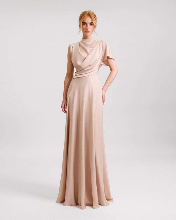 A long draped evening dress in beige color featuring a high collar and a cut-out at the back.