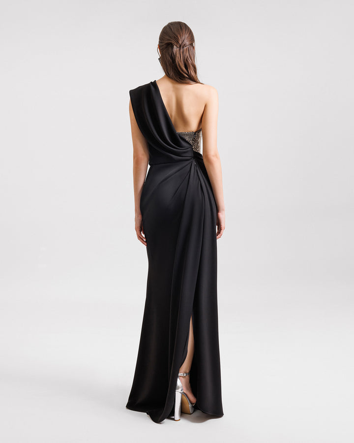 The back of a one-shoulder black evening dress with draping and a stone embellished corset.