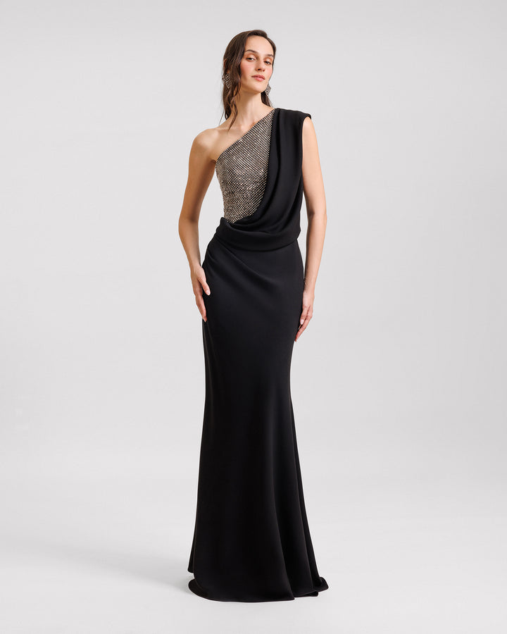 A one-shoulder black evening dress with draping and a stone embellished corset.