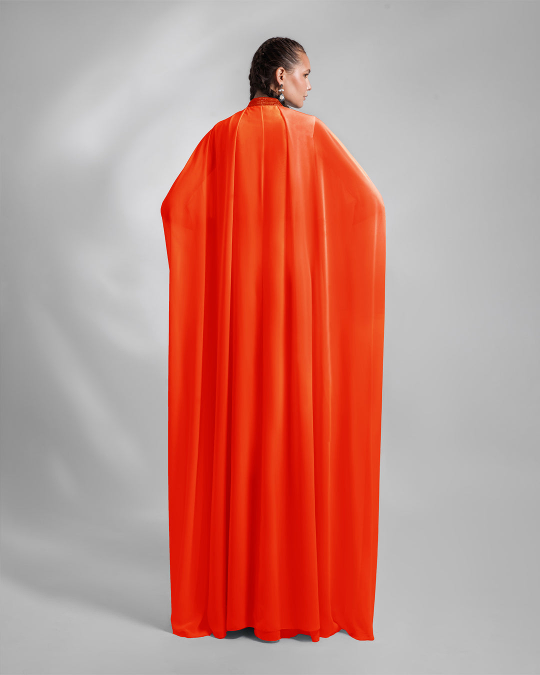 The back of long cape like kaftan style loose evening dress in orange chiffon fabric.