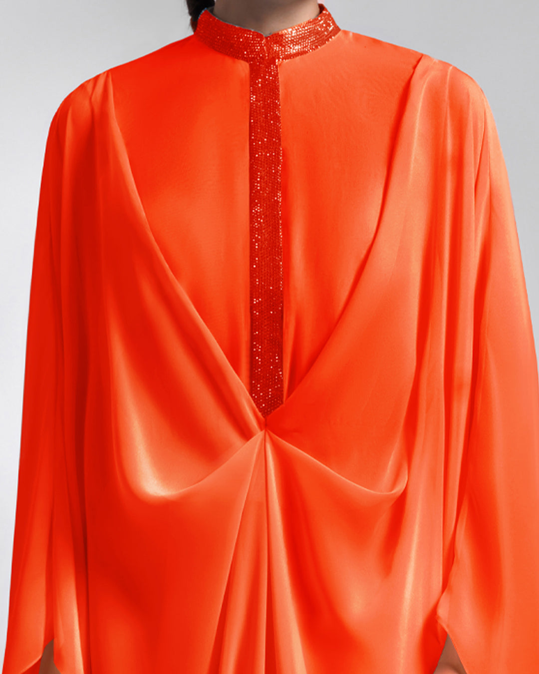 A close-up of a loose long chiffon evening dress with draping and embellishment details.