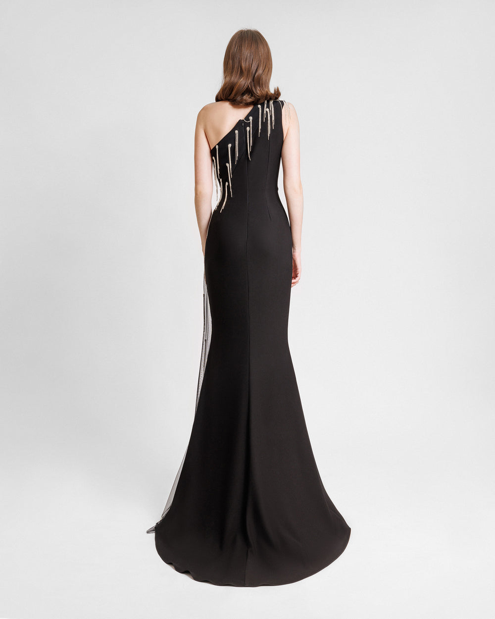 The back of a one-shoulder slim-cut black dress with beaded tulle along the side.