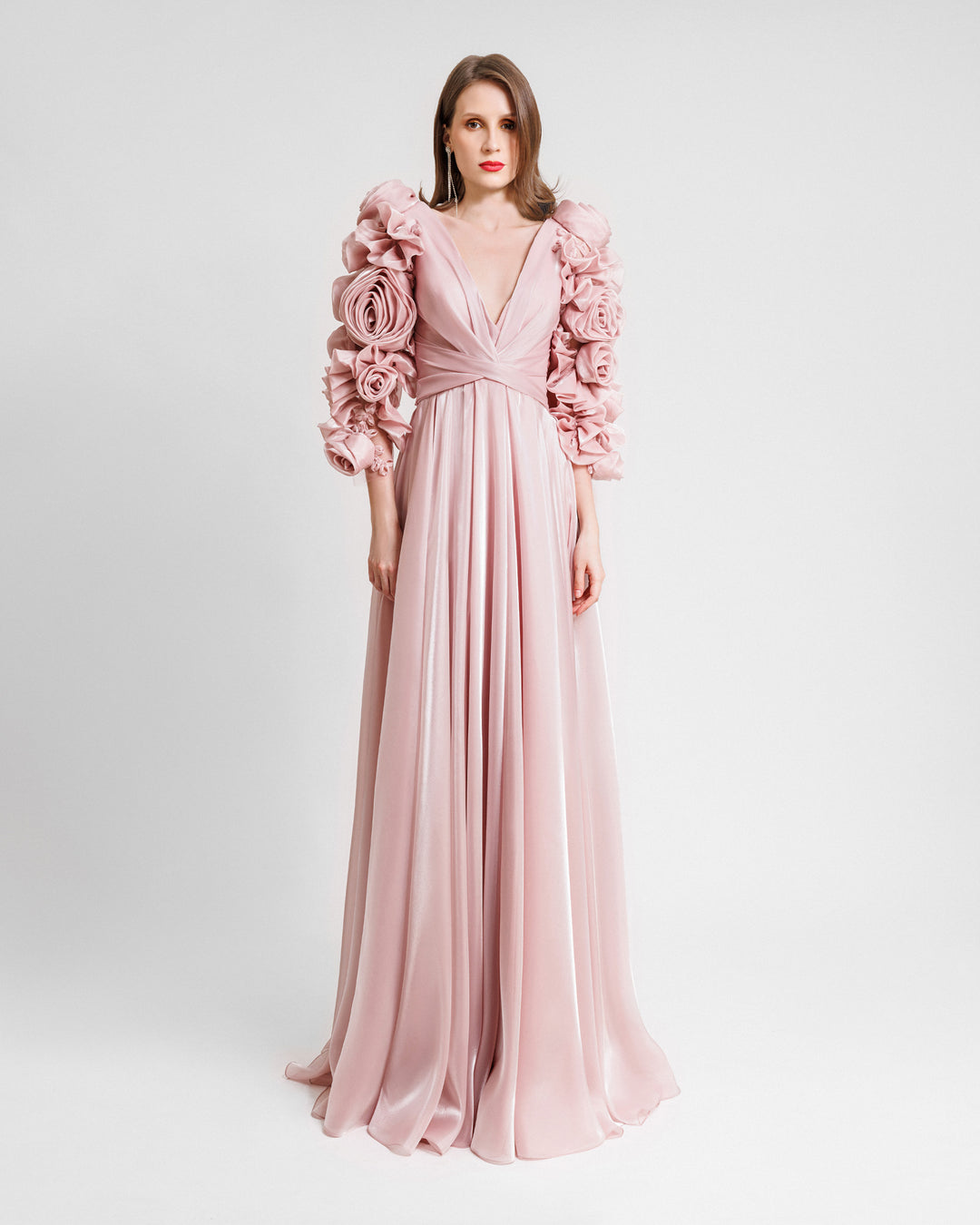 A deep V-neckline flared cut evening dress in pink color featuring draping on the waist and full floral sleeves.