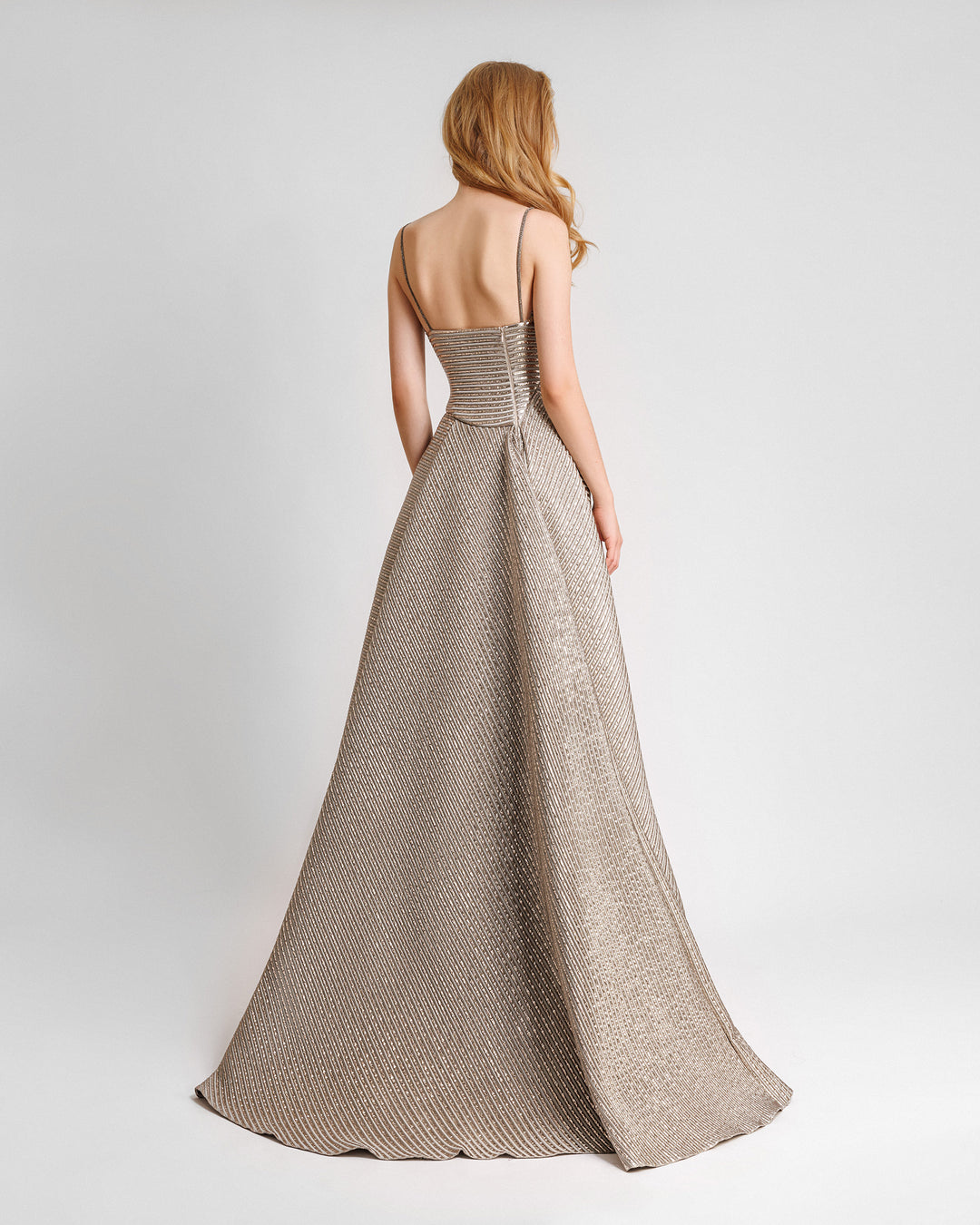 There back of a champagne evening dress featuring an asymmetrical waist cut and a full skirt.