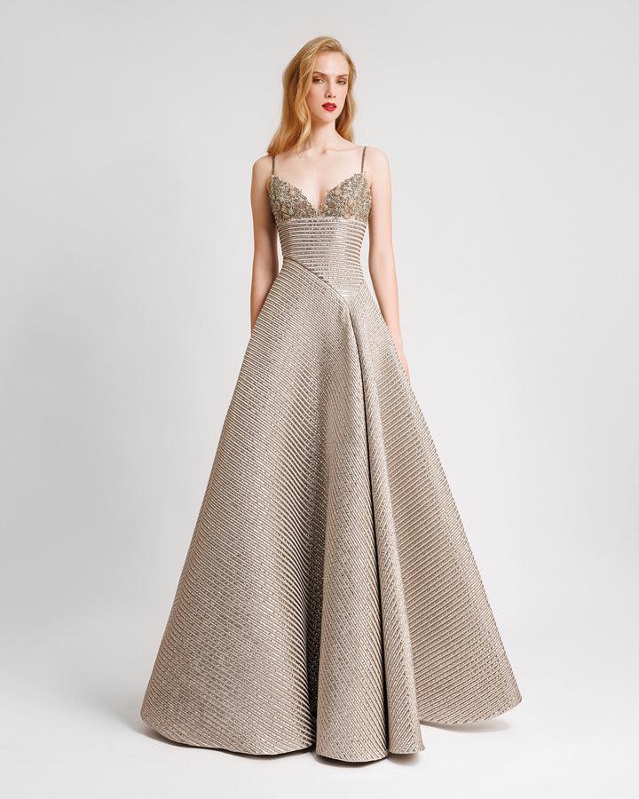 A beaded bust evening dress in champagne color featuring an asymmetrical waist cut and a full skirt.