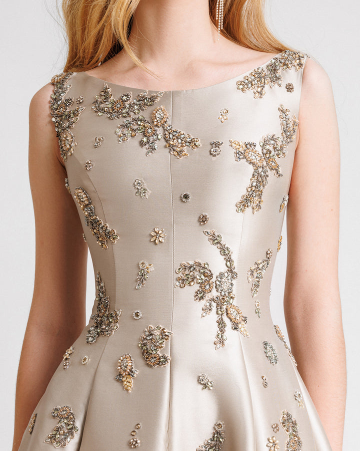 A close-up of a greige flared mikado evening dress featuring beaded embellishments.