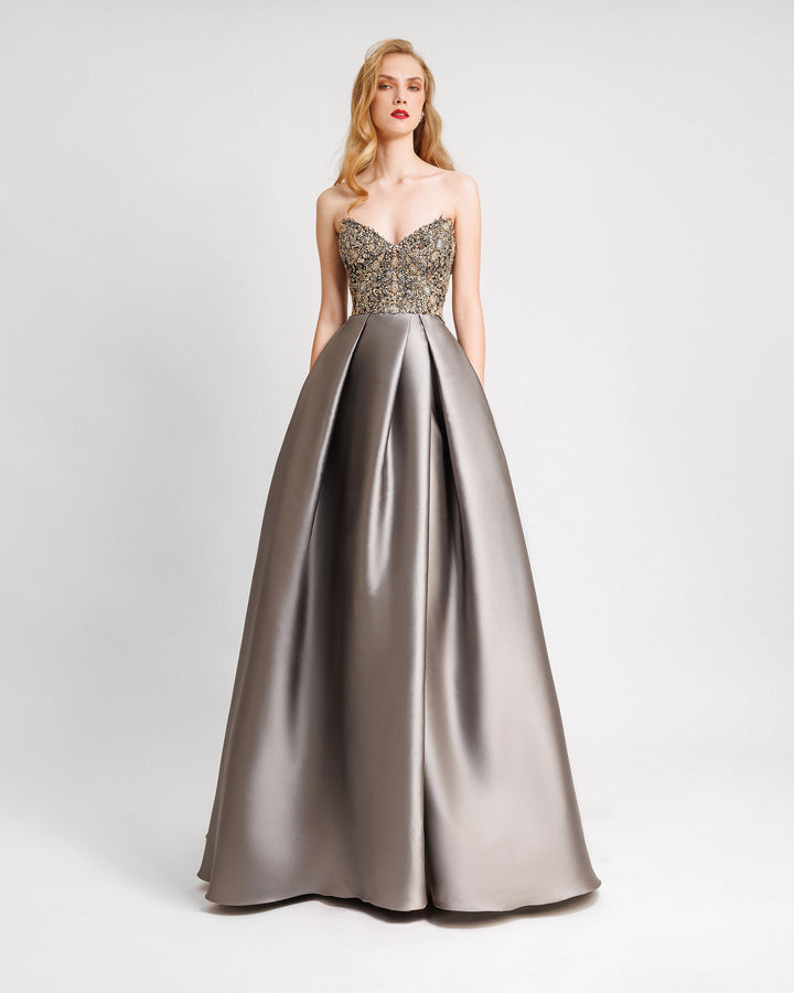 A strapless beaded corset evening dress with a draped full skirt featuring a slit on the side.