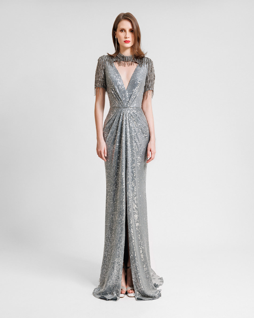 A grey evening dress featuring a deep v-neckline cut out, embroidered sequins neck and sleeves, and a slit at the front.