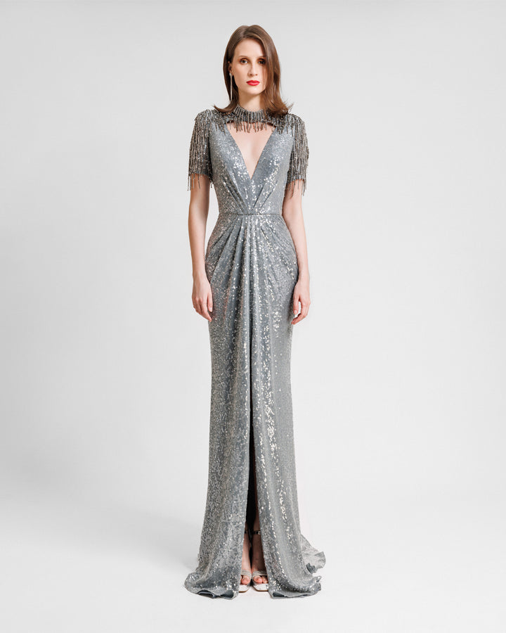 A grey evening dress featuring a deep v-neckline cut out, embroidered sequins neck and sleeves, and a slit at the front.