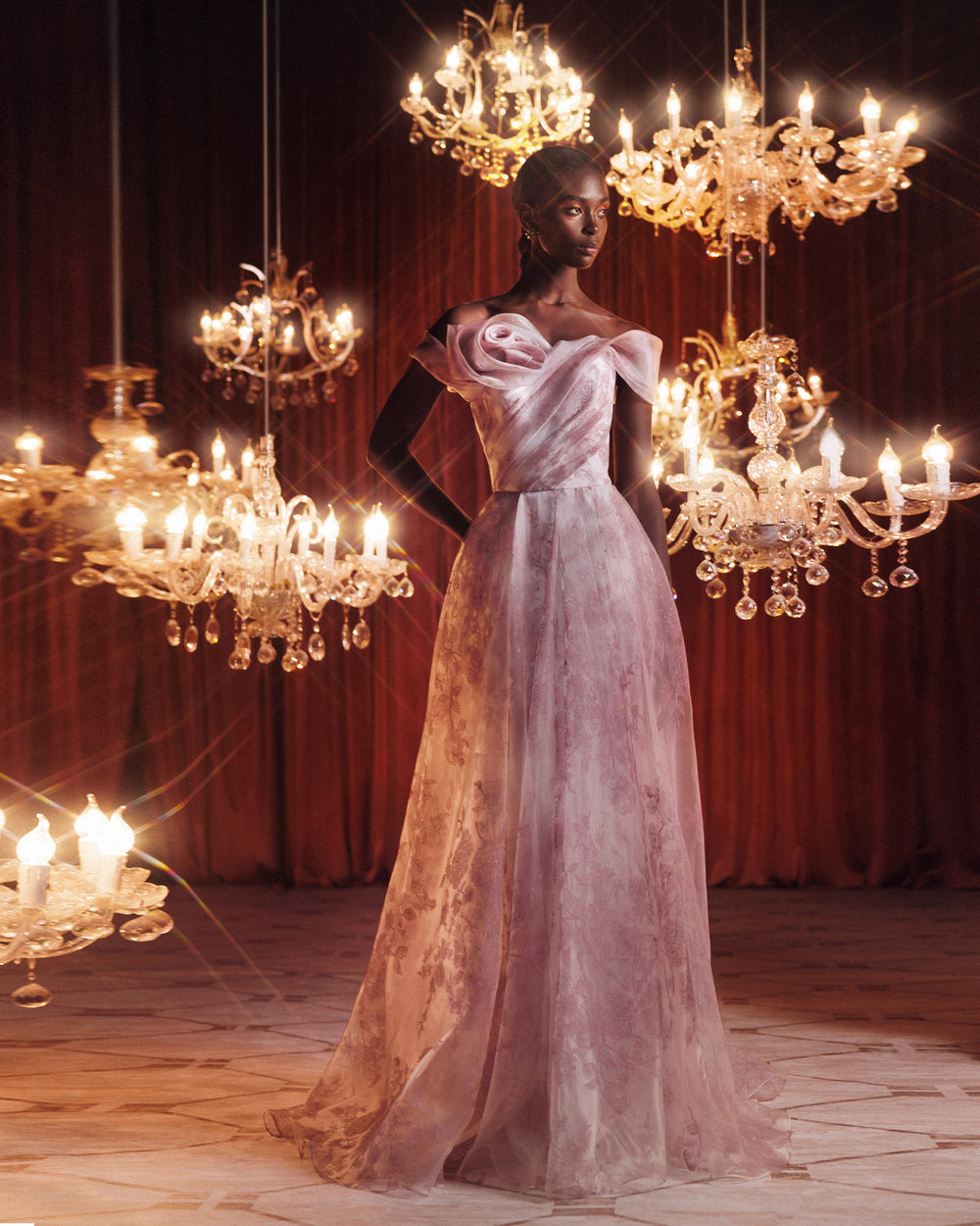 An off-the-shoulders pink evening dress with a floral draped neckline and a flowy skirt.