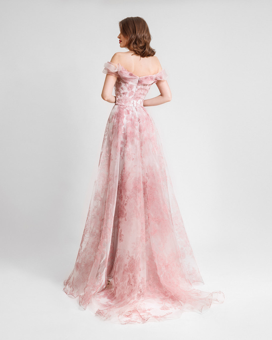 The back of an off-the-shoulders flowy  pink evening dress featuring floral prints.