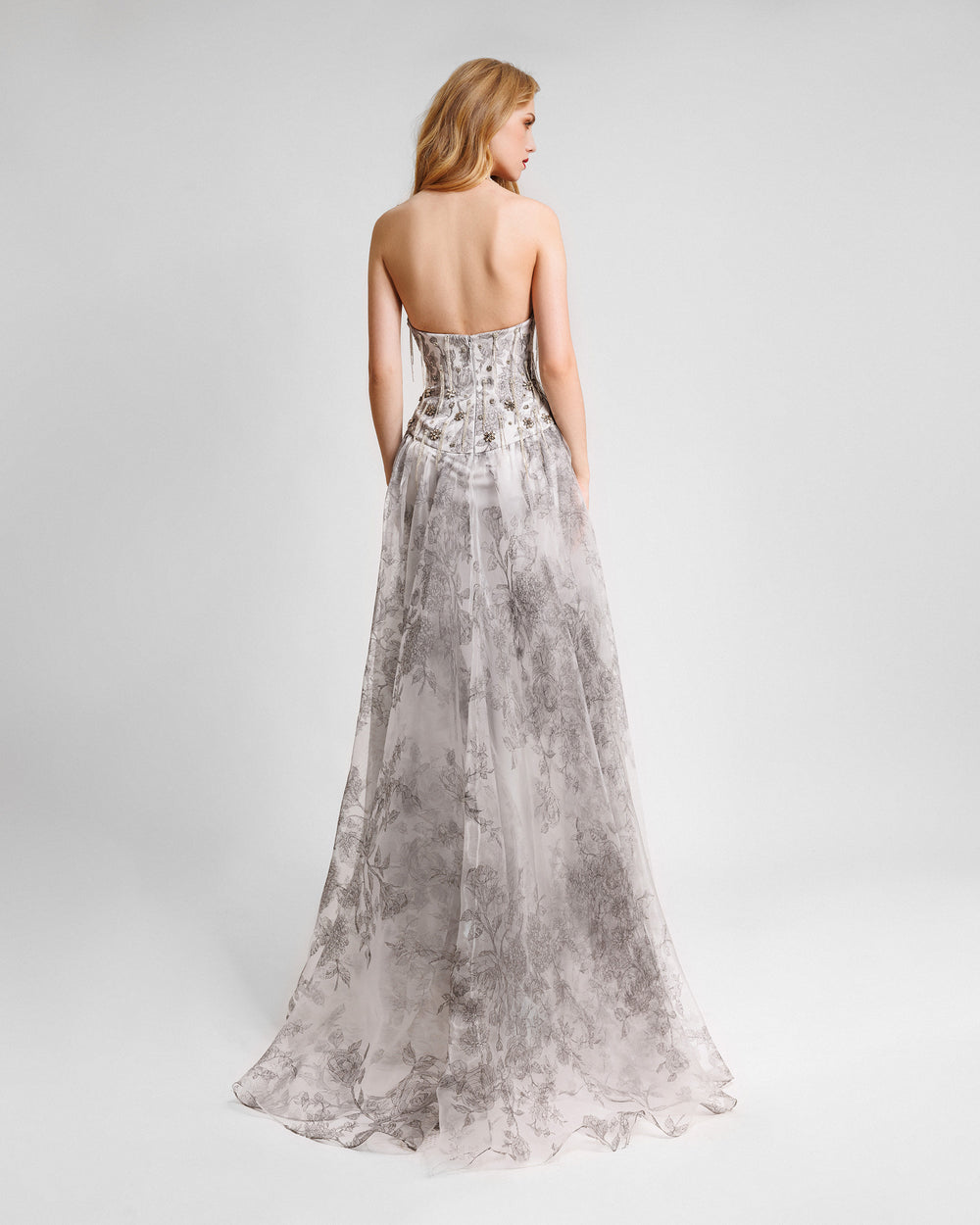 The back of a grey evening dress featuring floral prints and a strapless beaded corset.