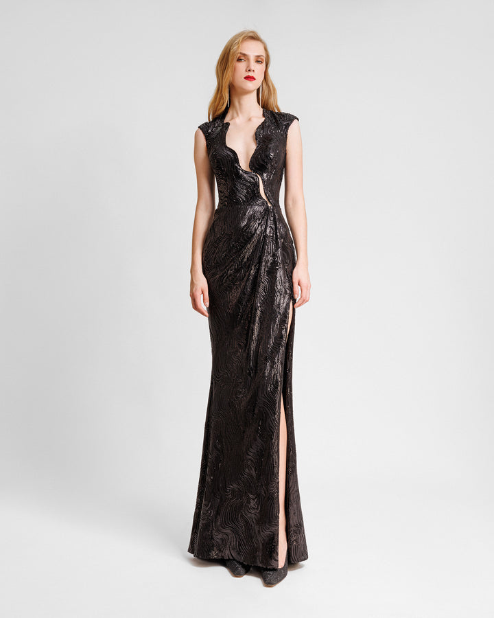 A slim-cut fully sequined black evening dress with a cut-out on the bodice and a slit on the side.