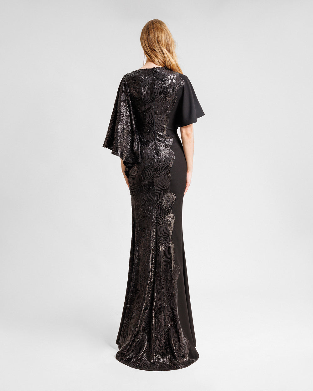 The back of an asymmetrical sleeves, embroidered sequins slim-cut black dress with a black crepe side.