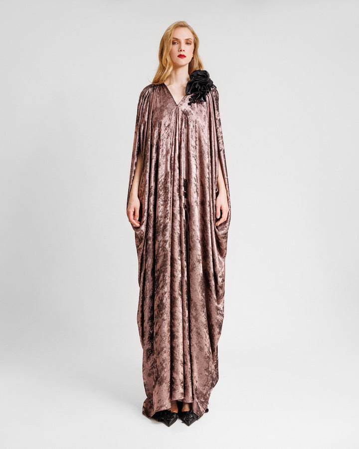 A v-neckline loose-cut kaftan dress in metallic pink with floral draping on the shoulder.