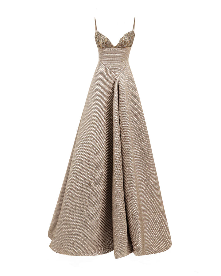 A beaded bust evening dress in champagne color featuring an asymmetrical waist cut and a full skirt.