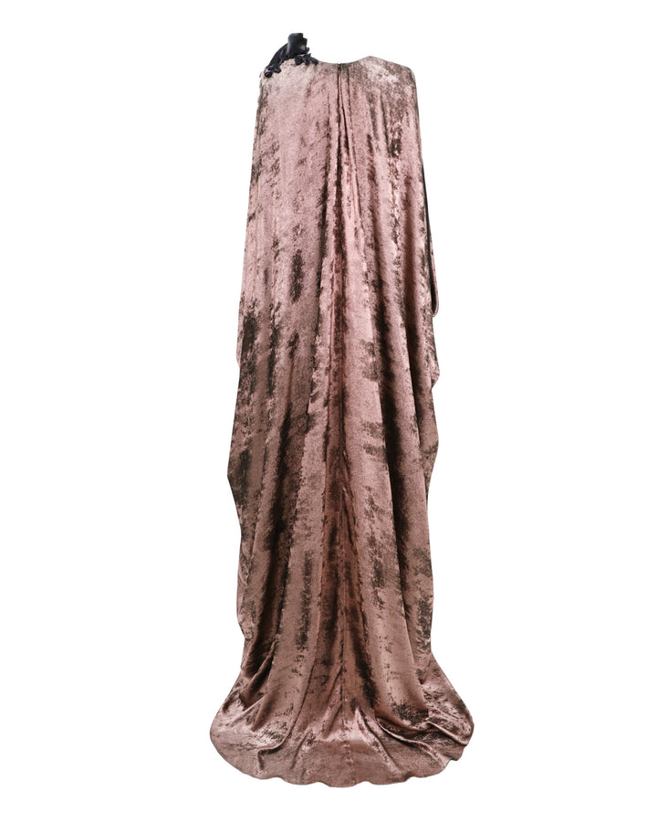 The back of a loose-cut kaftan dress in metallic pink with floral draping on the shoulder.