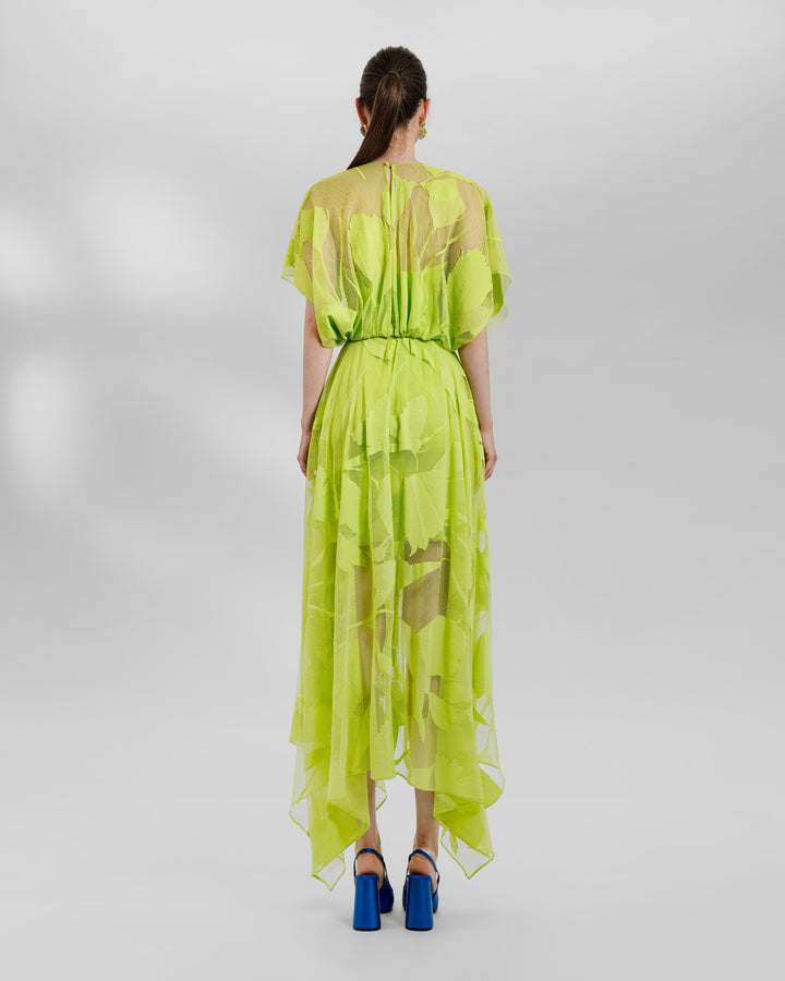 The back of a patterned lace midi dress with a bow design on the waist and an asymmetrical hemline, all in lime color.