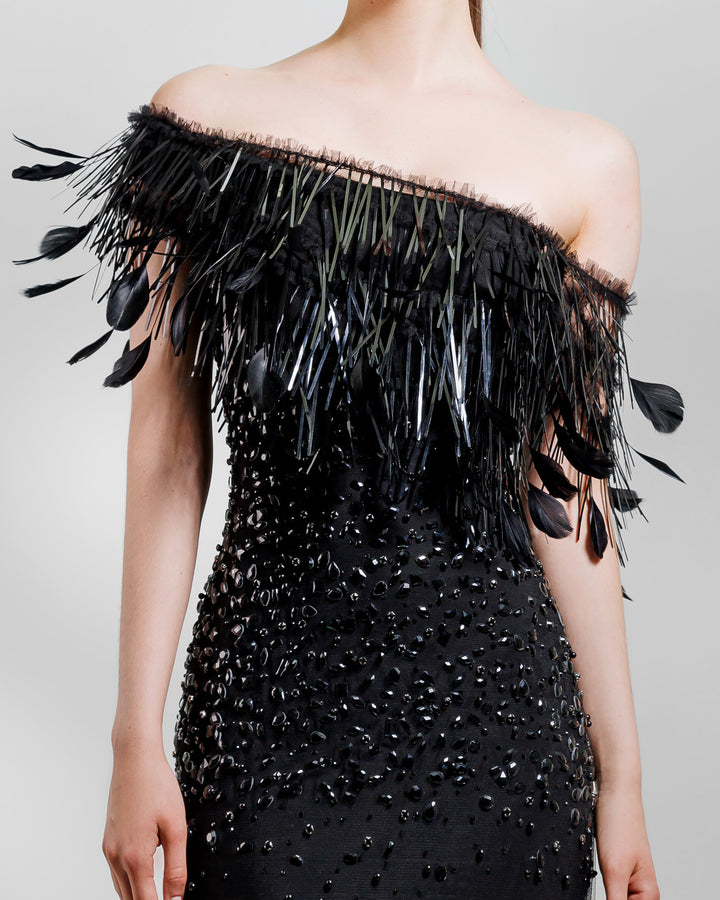 A close-up of an asymmetrical feather neckline fully beaded black evening dress.