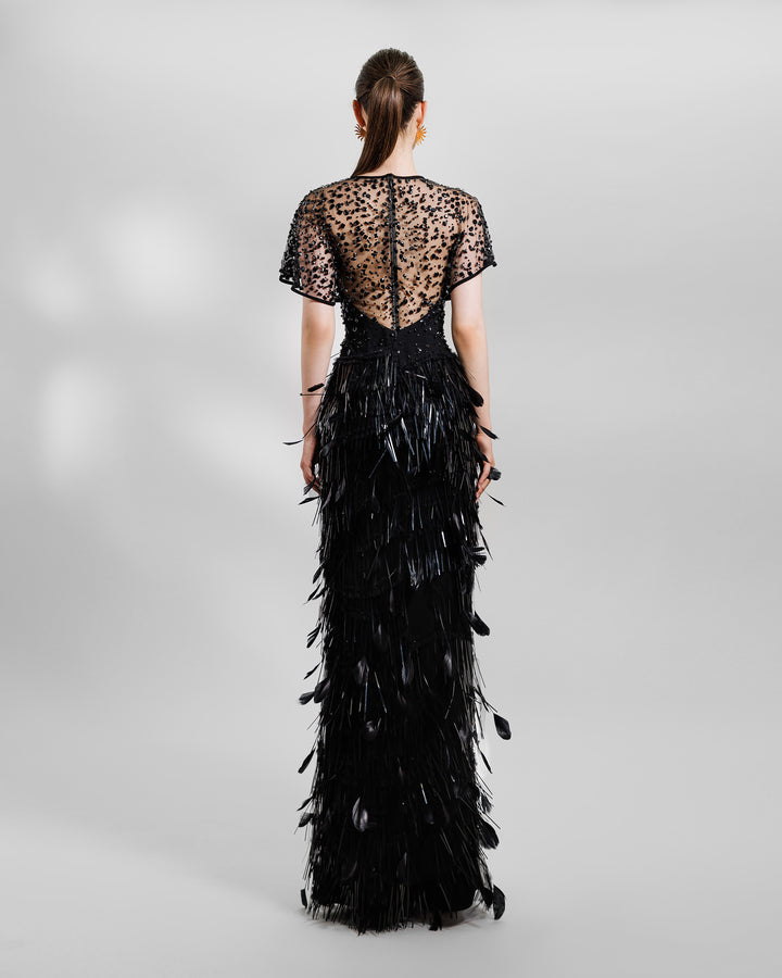 The back of a beaded corset slim-cut feather black evening dress featuring a slit on the side and a see-through back.