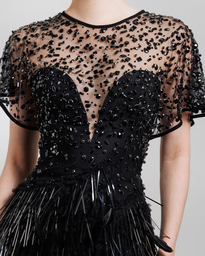 A close-up of a beaded corset slim-cut feather black evening dress featuring a slit on the side and a see-through back.