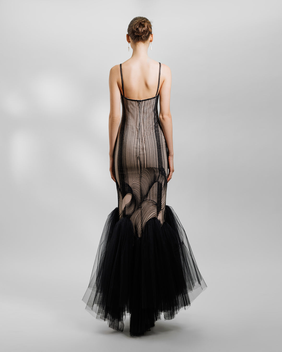 The back of an embroidered pattern black slim-cut dress with a gathered tulle hemline.