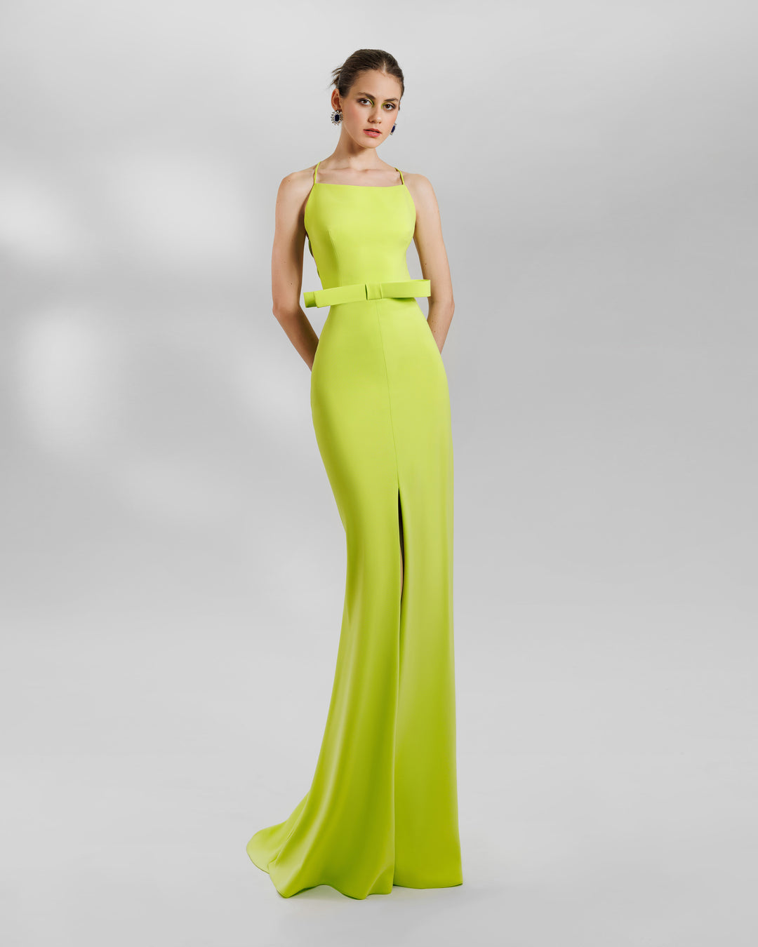 An open-laced back long lime evening dress featuring a statement bow on the waist and a middle slit.