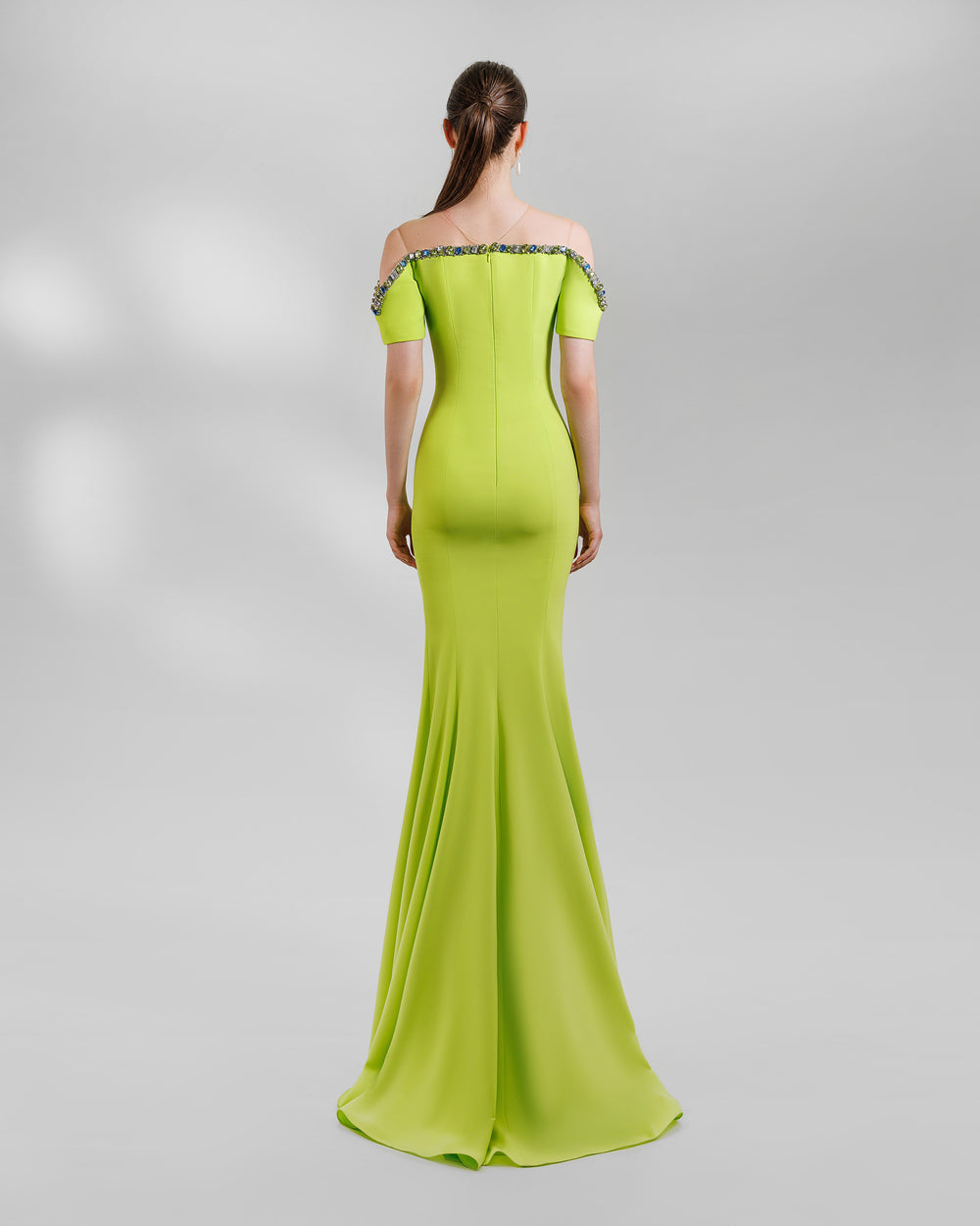 The back of a lime long evening dress with a beaded neckline that is off the shoulders. This design is featuring a mermaid cut.