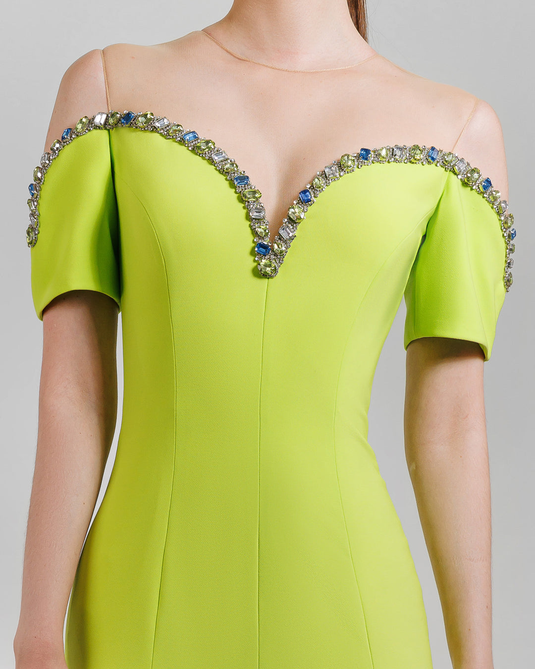 A close-up of a lime evening dress with a beaded neckline that is off the shoulders.