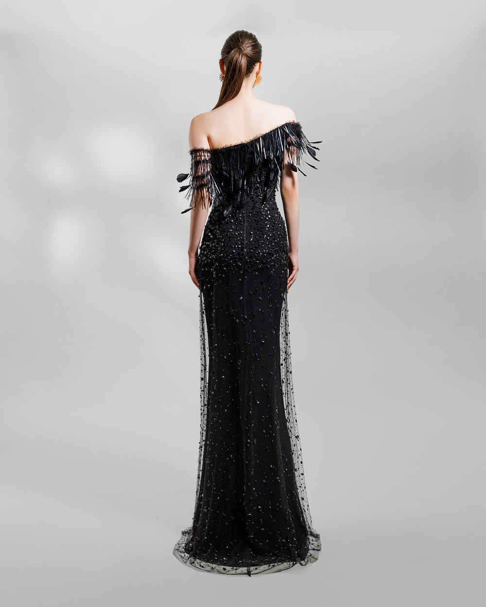 the back of an asymmetrical feather neckline fully beaded black evening dress.