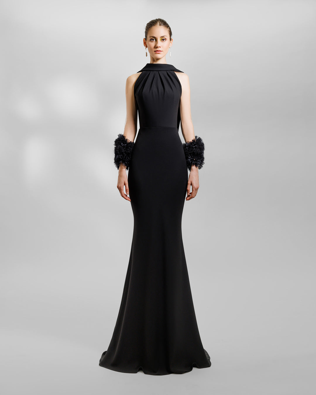 A halter-neck slim-cut black evening dress with a reversed collar, open back, and rushed organza details on the sleeves.