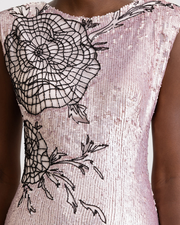 A close-up of a slim-cut embroidered sequins evening dress with structured shoulders and black floral embroideries.