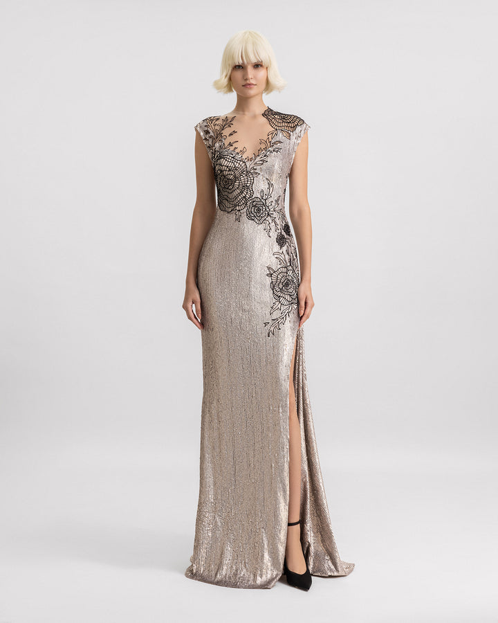 An embroidered sequins slim-cut evening dress in greige color with a black beaded floral design, a V-neckline, and a slit on the side.