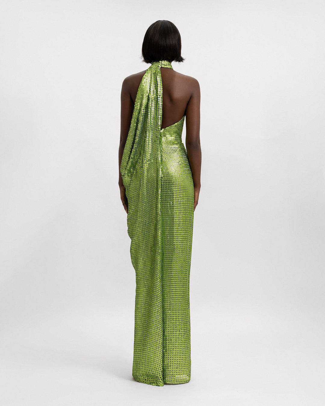 The back of a halter neckline full sequins evening dress in green with side draping details.