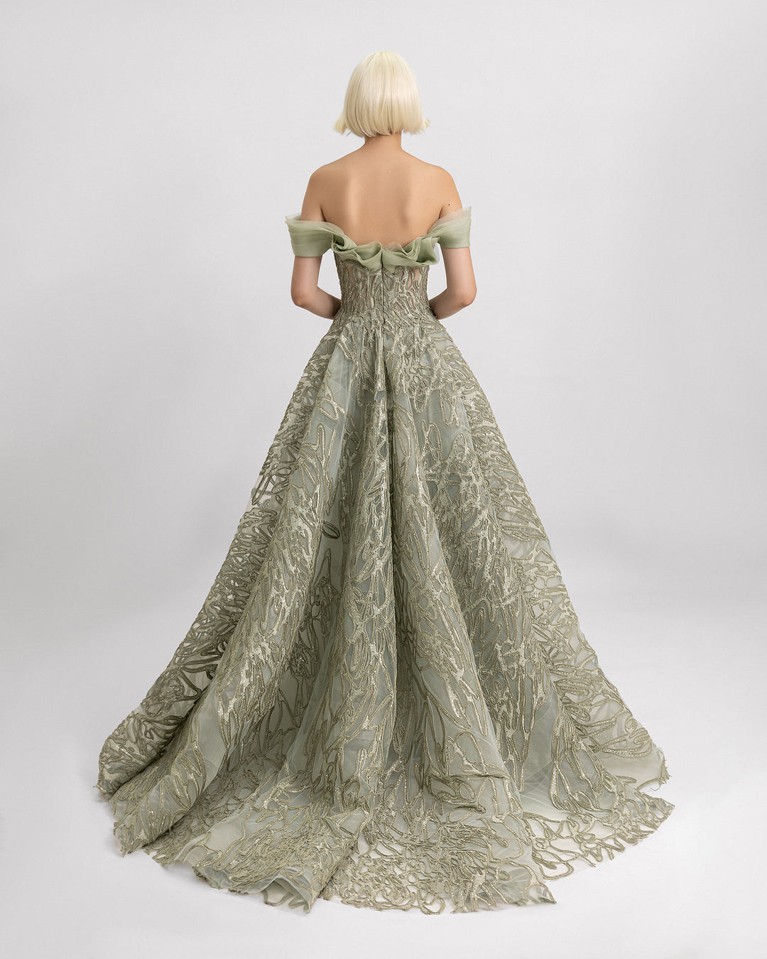 The back of an off-the-shoulder sage evening dress with organza draping at the neckline and a draped skirt.