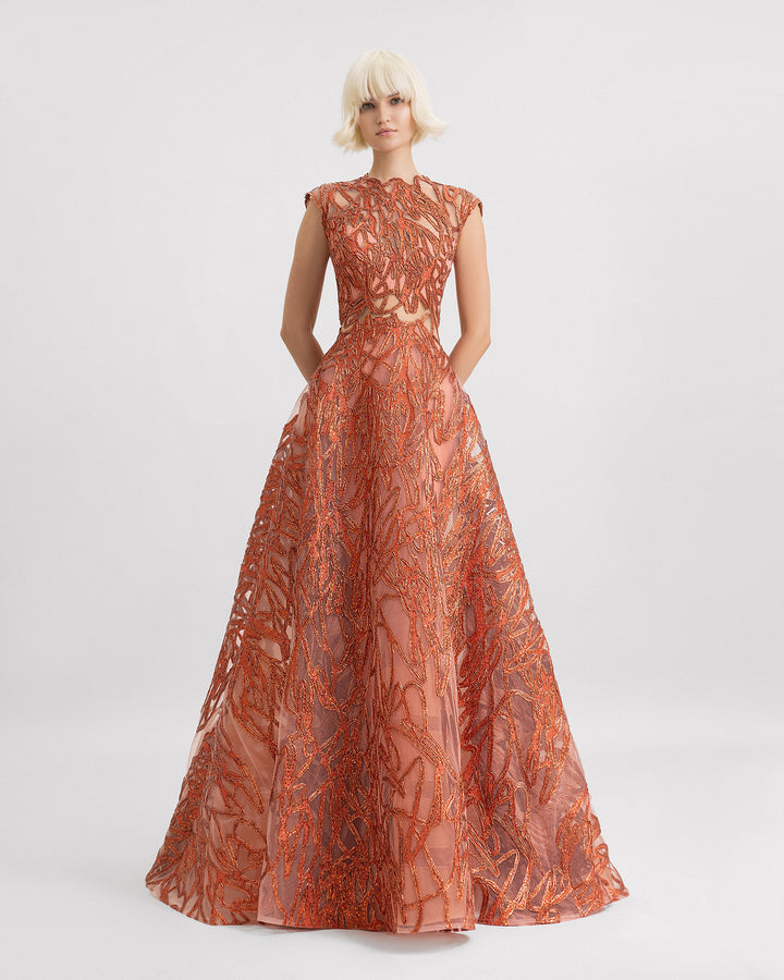 A cap sleeves evening gown in copper color with see-through waist details and a wide skirt.