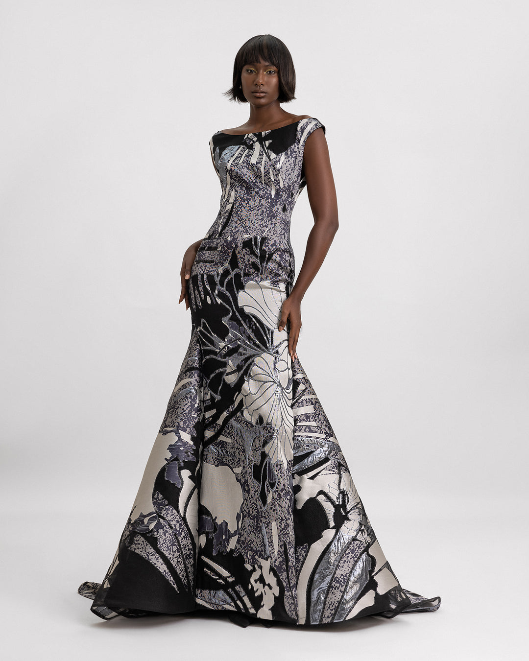 A boat neckline slim cut dress with a mermaid cut illusion, in a printed jacquard devoré in black, grey hues and champagne color. 