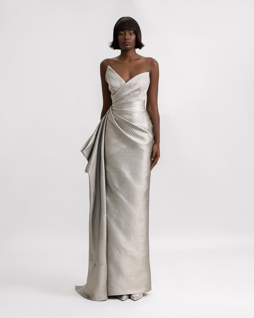 An asymmetrical neckline draped evening dress in greige jacquard with draped details on the side.