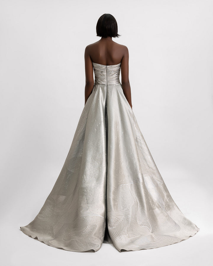 The back of a strapless draped evening gown in greige jacquard with beaded details on the corset.