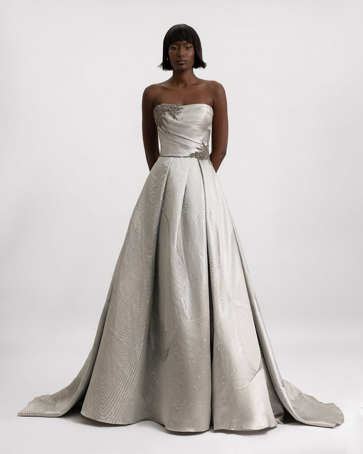 A strapless draped evening gown in greige jacquard with beaded details on the corset.