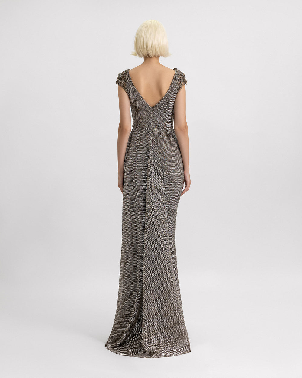 A v-shape open back evening dress in grey metallic jersey featuring beadings and a draped train.