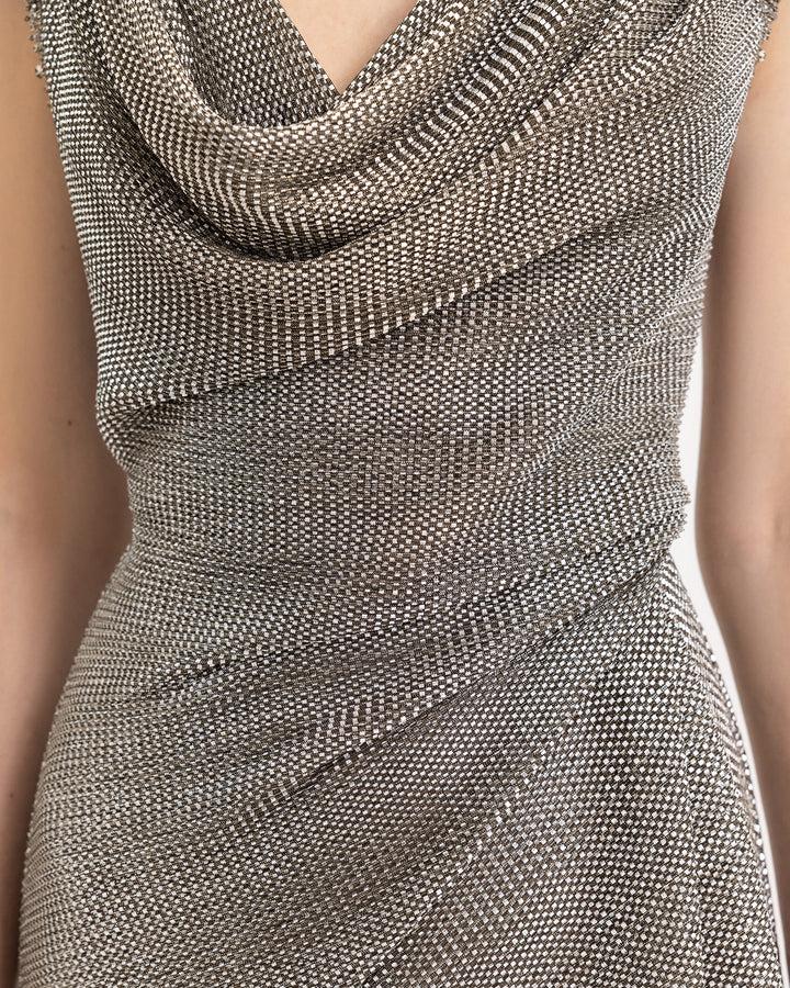 A close-up of a draped cowl-neckline and waist evening dress in grey metallic jersey.