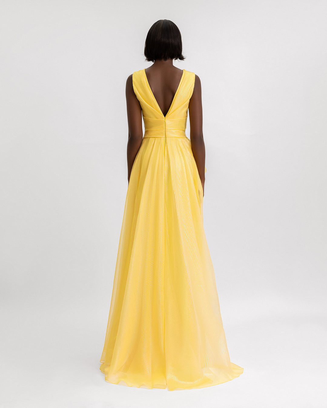 A v-shaped open back evening dress in yellow organza lamé.