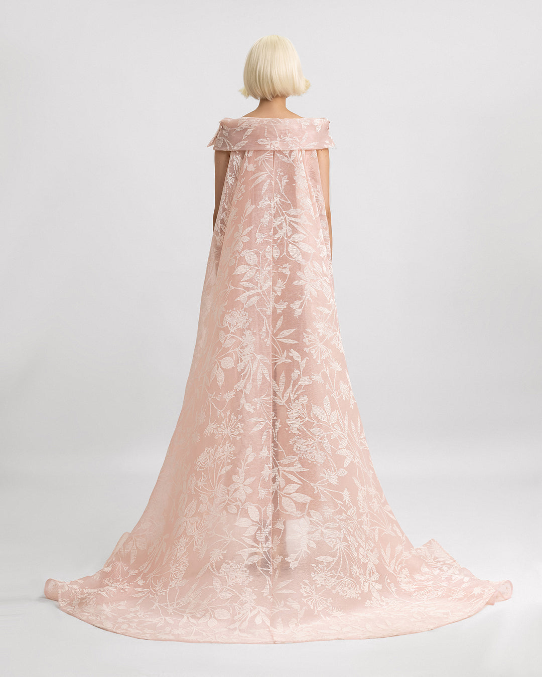 The back of a light pink organza Jacquard evening dress featuring a reversed collar and a long cape.