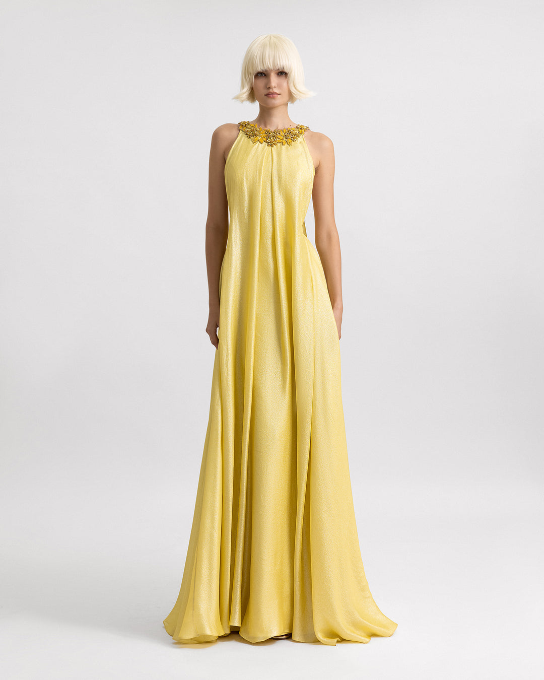 A loose-cut yellow evening dress with beadings on the neckline, and side openings on the corset.