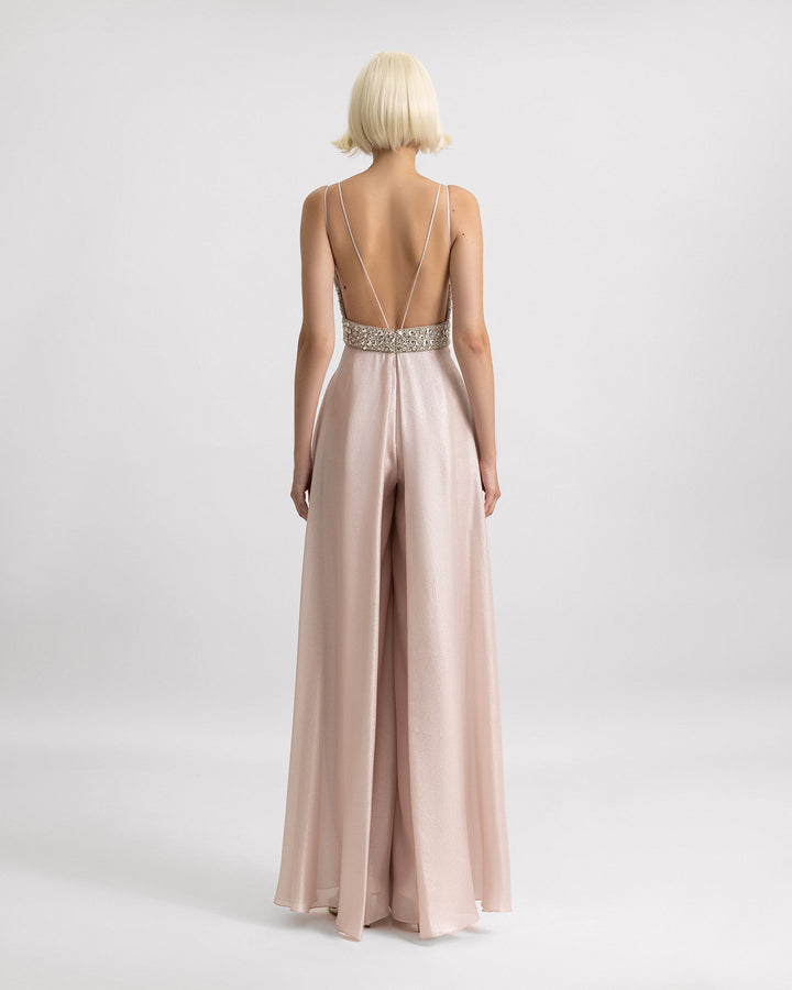 An open back light pink jumpsuit with lower back beadings and flared pants.