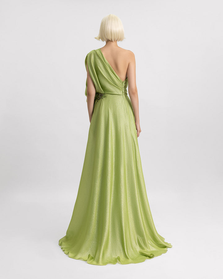 The back of a one-shoulder green evening dress with draping details and beadings on the waistline.