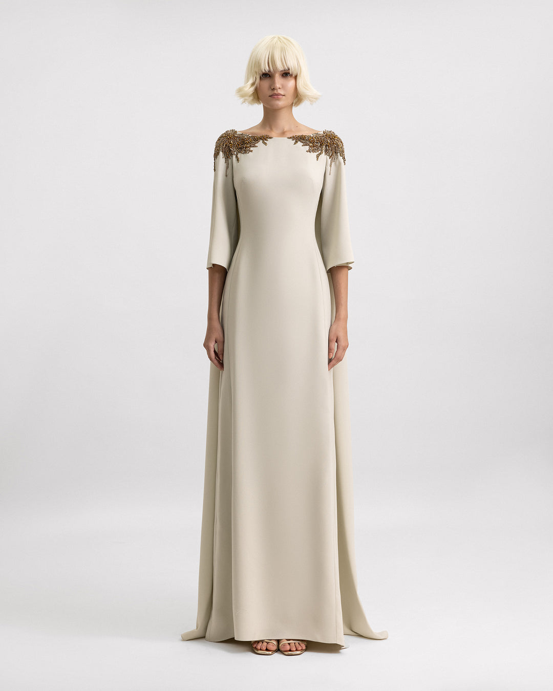 A three-quarter sleeves evening dress in pale sage with beadings on the shoulders and a cape-like back.